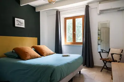 a bedroom with a bed with blue sheets and a window at Maison d’Etienne in Lacoste