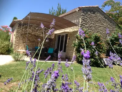 a stone house with purple flowers in front of it at Au bastidon de Gordes in Gordes