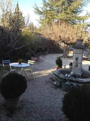 a garden with a fountain and a table and trees at L'Oustalet in La Tour-dʼAigues