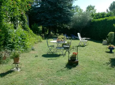 a garden with a table and chairs in the grass at L'Oustalet in La Tour-dʼAigues