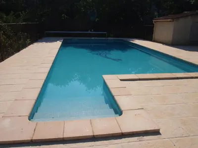 a swimming pool with blue water in a backyard at Les Buis in Carpentras