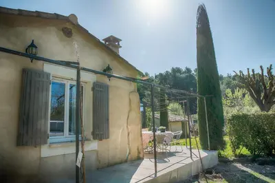 a house with a patio with a table and a window at A jewel by the river! in Fontaine-de-Vaucluse