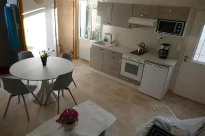 a kitchen with a white table and chairs and a table and a room at Les Hauts De Reillanne in Reillanne