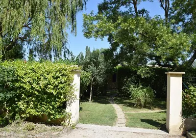 a garden with a gate and a hedge at La Maison Des Invites in Pernes-les-Fontaines