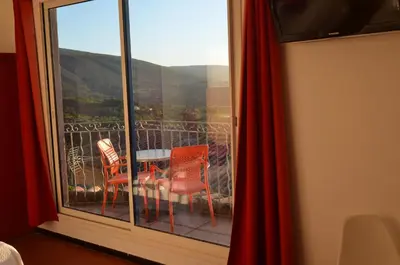 a balcony with a table and chairs and a window at Logis Hôtel Panoramique César in Bonnieux