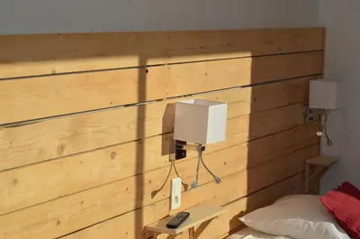 a bedroom with a wooden wall with two lights on it at Logis Hôtel Panoramique César in Bonnieux
