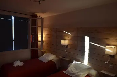 a hotel room with two beds and a window at Logis Hôtel Panoramique César in Bonnieux