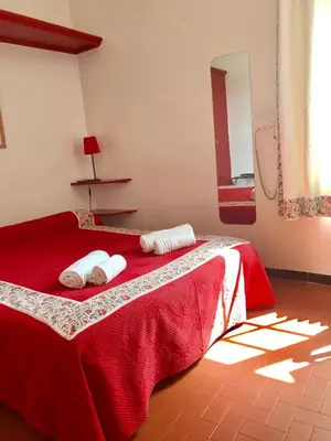 a bedroom with a red bed with towels on it at Logis Hôtel Panoramique César in Bonnieux