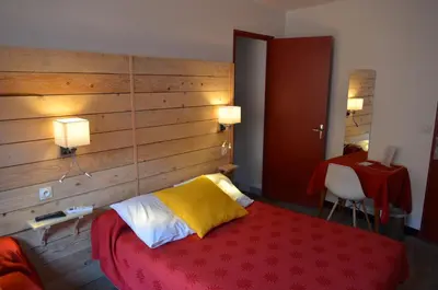 a bedroom with a red bed with a wooden wall at Logis Hôtel Panoramique César in Bonnieux
