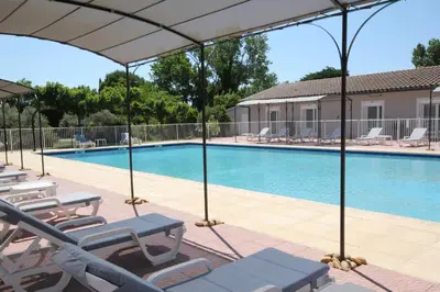 a swimming pool with chaise lounge chairs and an umbrella at Hôtel Saint Louis in Le Thor