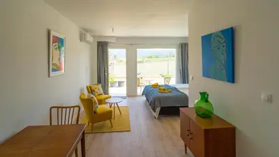 a living room with a bed and a room with a table at Les Terrasses de Cascavelle in Blauvac