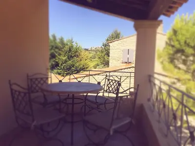 a patio with a table and chairs on a balcony at Entre Vignes et Collines in Méthamis