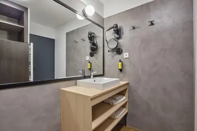 a bathroom with a sink and a mirror at Appart'hôtel Odalys City - Aix en Provence Centre Rotonde in Aix-en-Provence