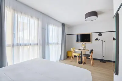 a hotel room with a bed and a table with chairs at Appart'hôtel Odalys City - Aix en Provence Centre Rotonde in Aix-en-Provence