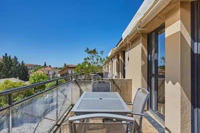 a patio with a table and chairs on a balcony at Appart'hôtel Odalys City - Aix en Provence Centre Rotonde in Aix-en-Provence