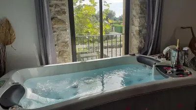 a bath tub with a view of a window at Le Mas Romantique avec Jacuzzi et Sauna privé in Sénas