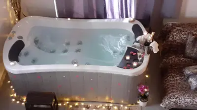 a bath tub in a room with christmas lights at Le Mas Romantique avec Jacuzzi et Sauna privé in Sénas