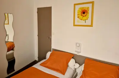 a bedroom with a bed with orange pillows and a mirror at Le palais, hôtel - restaurant in Apt