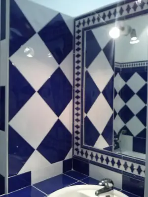 a bathroom with blue and white tiled walls and a mirror at Les Restanques in Goult