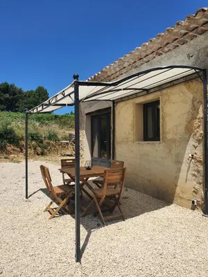 a table and chairs under a canopy in front of a house at Bastide Bellugue Maison d'hôtes réseau Bienvenue à La Ferme à 3 minutes de Lourmarin in Cadenet