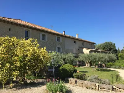 a large stone building with a garden in front of it at Domaine La Condamine CRILLON LE BRAVE in Crillon-le-Brave
