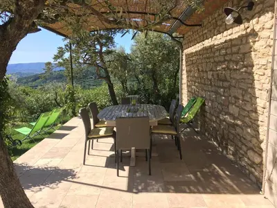 a table and chairs on a patio with a stone wall at Mas De Gordes in Gordes