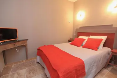 a bedroom with a bed with red pillows and a television at Mas De Gordes in Gordes