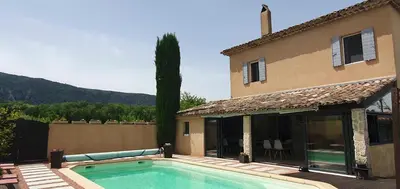 a villa with a swimming pool in front of a house at Le Jardin d'Ivana in Oppède