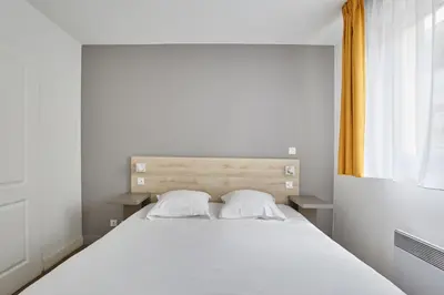 a bedroom with a large white bed with two pillows at Appart'hôtel Odalys City - Aix en Provence Ouest in Aix-en-Provence