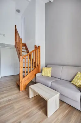 a living room with a couch and a staircase at Appart'hôtel Odalys City - Aix en Provence Ouest in Aix-en-Provence