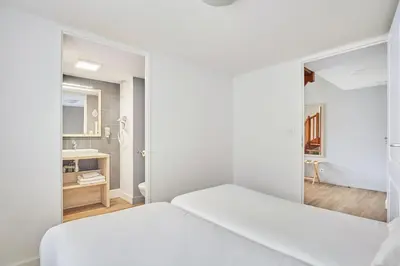 a white room with a bed and a bathroom at Appart'hôtel Odalys City - Aix en Provence Ouest in Aix-en-Provence
