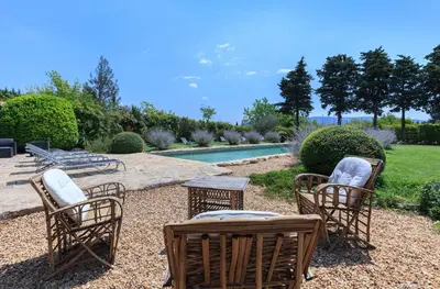 a group of chairs and tables next to a pool at La Louvière des Bruyères in Robion en Luberon