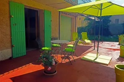 a patio with a table and chairs and an umbrella at Envies en Lubéron in Saignon