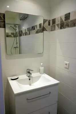 a white bathroom with a sink and a mirror at Envies en Lubéron in Saignon