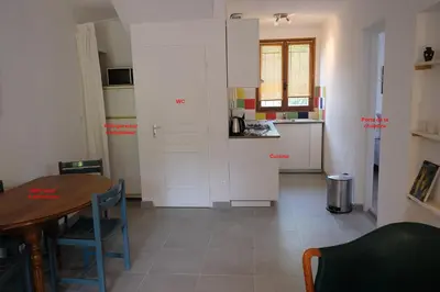 a room with a table and a kitchen with white cabinets at Envies en Lubéron in Saignon