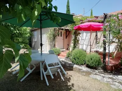 a table and chairs under an umbrella in a garden at Maison Charrasse in Flassan