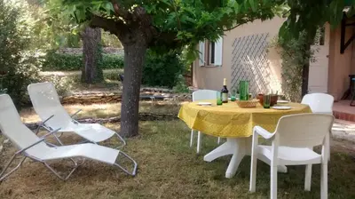 a table and chairs under a tree in a yard at Maison Charrasse in Flassan