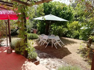 a table and chairs under an umbrella in a garden at Maison Charrasse in Flassan