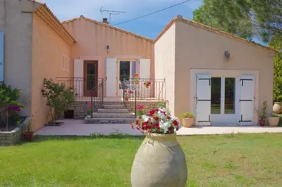 a large vase with flowers in front of a house at Les murmures du Temps Villa 3 Chambres avec Piscine in Carpentras
