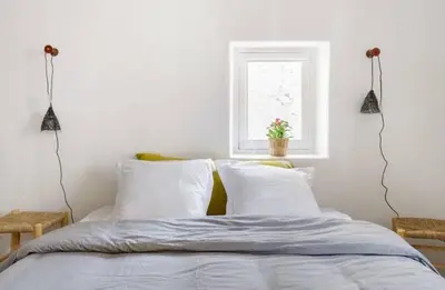 a bedroom with a bed with white sheets and a window at Nuits étoilées Lourmarin in Lourmarin