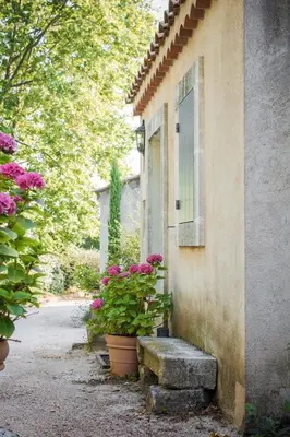 a building with a bench next to a window with flowers at Les Mazets de Marie de Jules in Eyragues