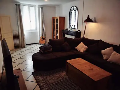 a living room with a brown couch and a guitar at La maison Bleue in Céreste