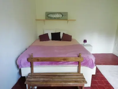 a bedroom with a bed with a wooden bench at La maison Bleue in Céreste