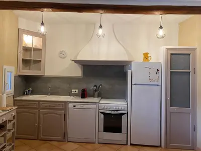 a kitchen with a white refrigerator and a stove at Villa confortable à Caromb avec piscine privée in Caromb