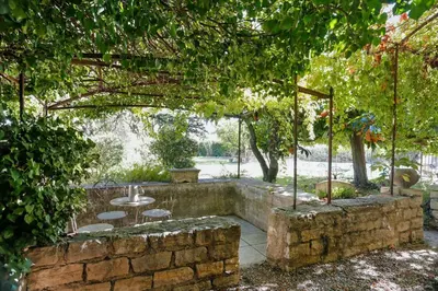 a patio with a table and chairs under a tree at Villa confortable à Caromb avec piscine privée in Caromb