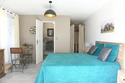 a bedroom with a blue bed and a dining room at Chambre d'hôtes du Charme Provençal in Sénas