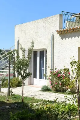 a white building with a door and some flowers at Chambre d'hôtes du Charme Provençal in Sénas