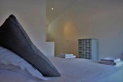 a bed with a black pillow on top of it at Le Chat Sur Le Toit in Lourmarin