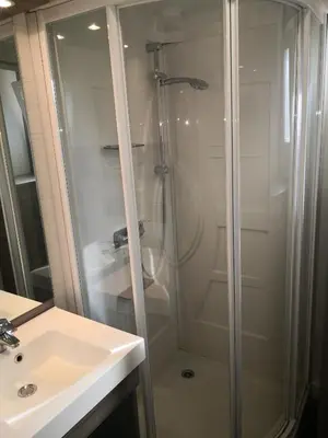 a shower with a glass door next to a sink at La Colline des Ocres Village de vacances 3 étoiles in Apt
