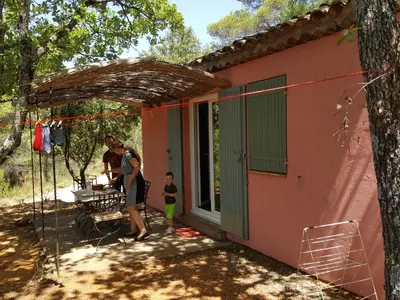 a woman and a child standing outside of a pink house at La Colline des Ocres Village de vacances 3 étoiles in Apt